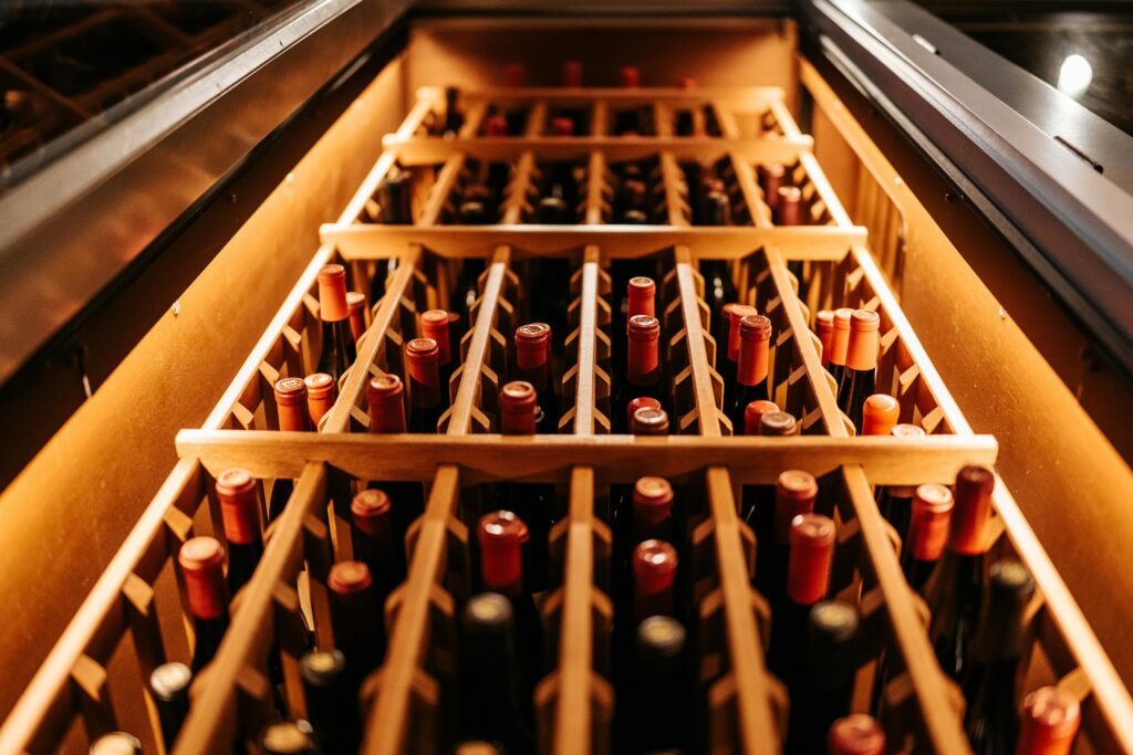 A warm-toned close-up of bottled wine stored in a wooden rack, perfect for a winery or wine cellar concept.